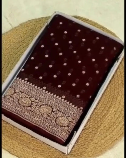 A boxed dark maroon fabric item with small metallic dot embellishments and an ornate embroidered border, placed on a woven straw mat against a light beige background.