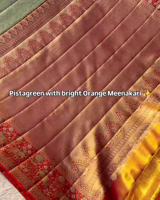 A close-up of a folded saree fabric in pistachio green with bright orange and gold zari embroidery, featuring a red border and floral motifs. Text overlay reads 'Pistachio green with bright Orange Meenakari'.