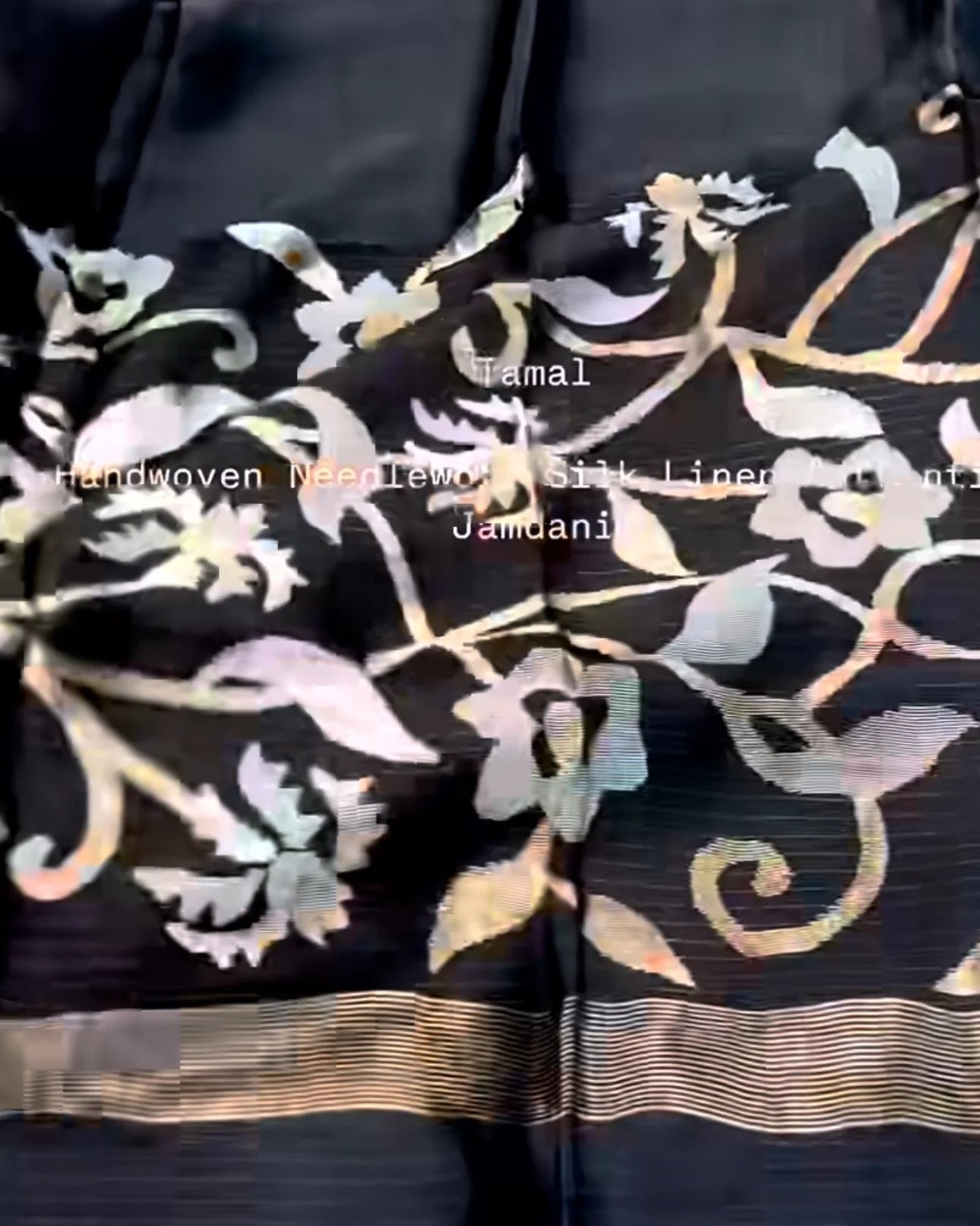 black silk lining fabric with a gold and silver floral brocade border, featuring a striped gold zari band and a watermark text overlay.